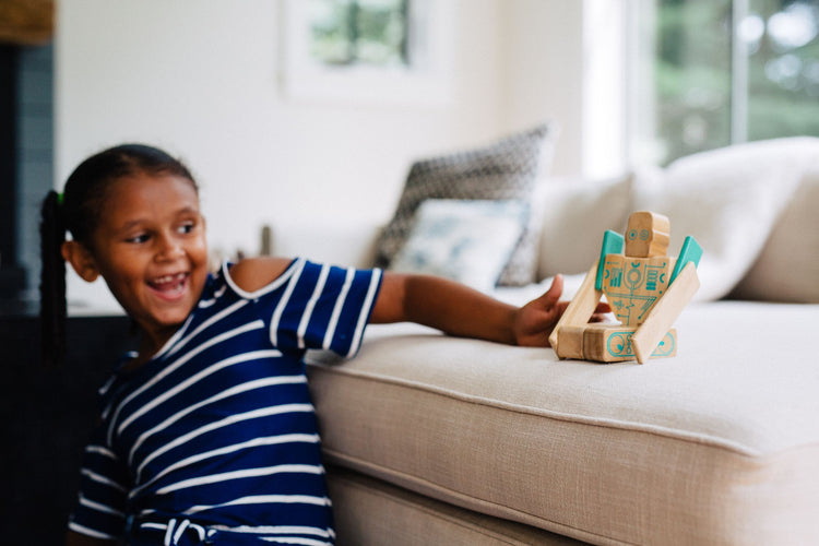 Tegu UK magnetic wooden building blocks - girl playing with Magbot