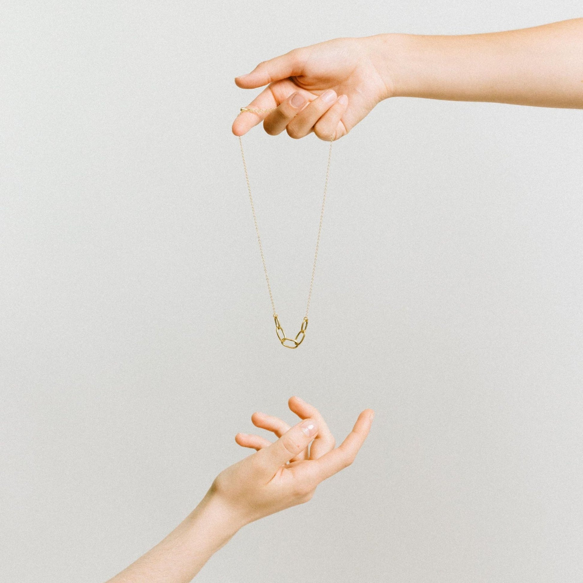 Infinite Necklace  Empowering Women in Uganda - brass chain necklace - between hands