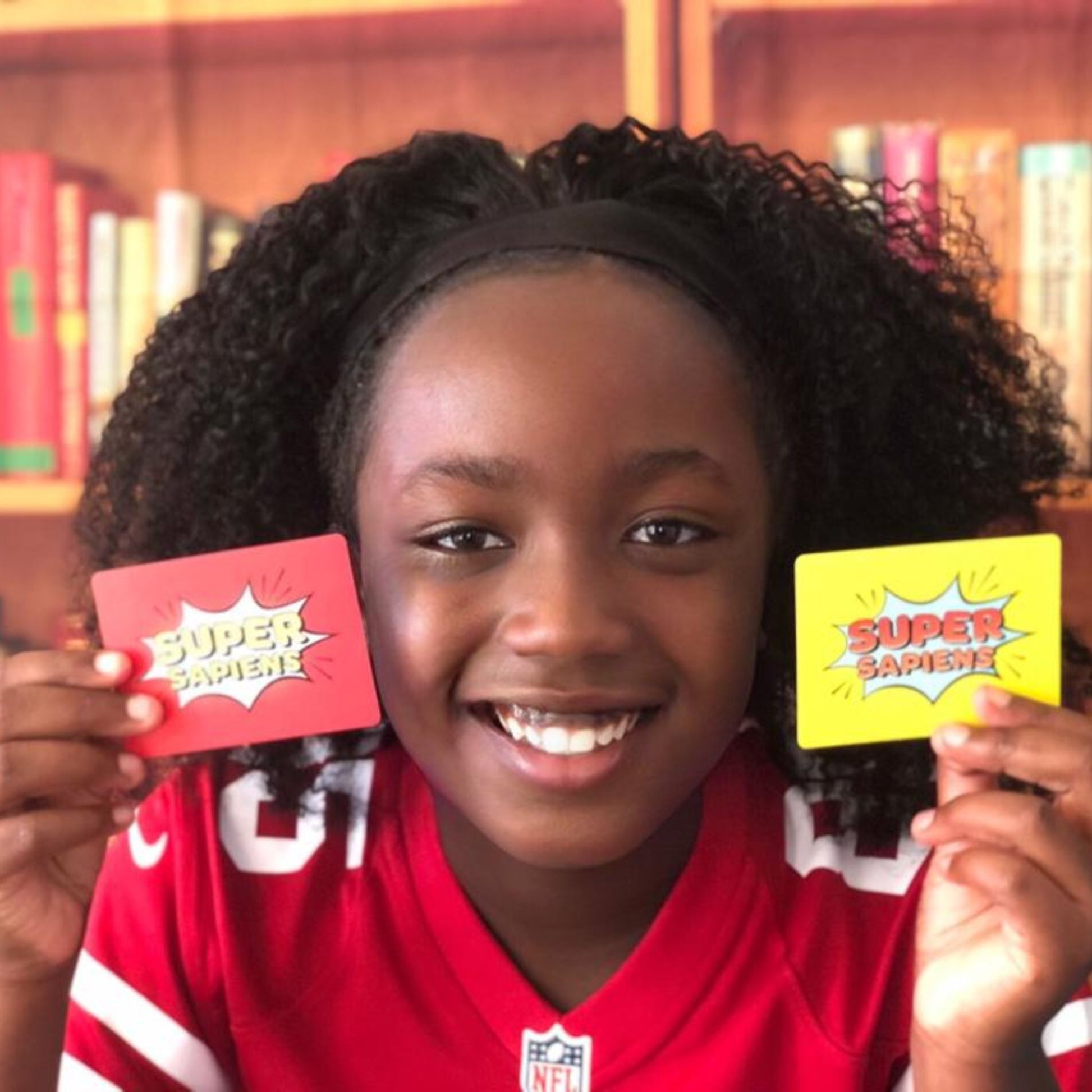 Super Sapiens  A 3-in-1 Game to Help Change the World - girl holds cards
